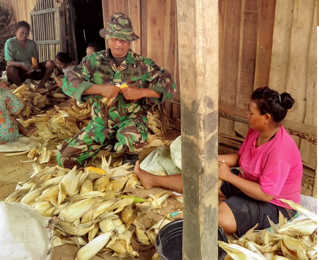 Anggota Satgas Bantu Kupas Jagung