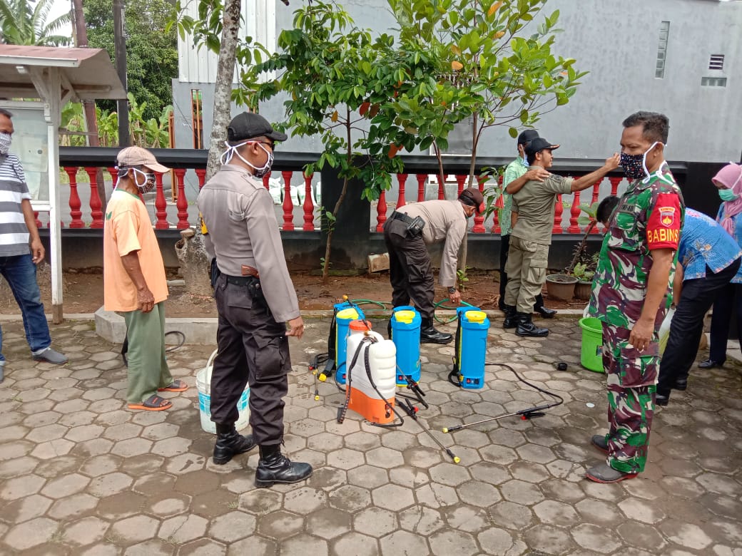 Satgas TMMD Bersama Polri Bantu Warga Semprot Disinfektan.