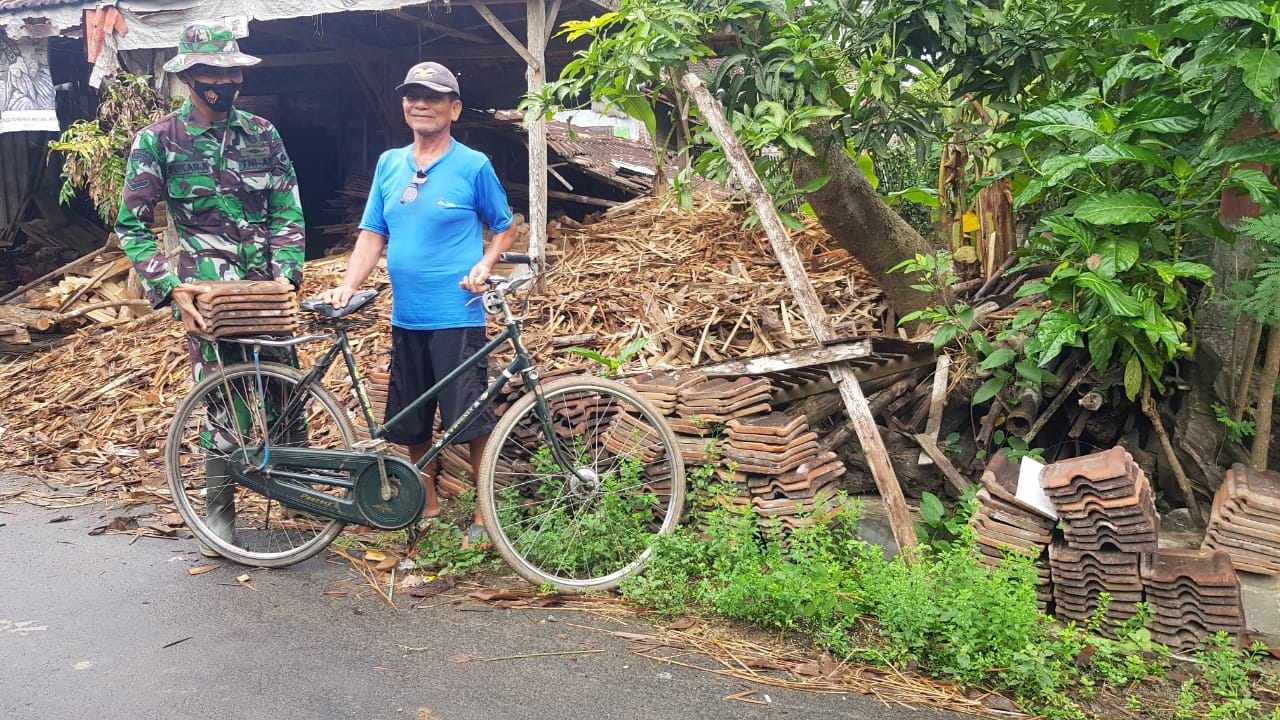 Anggota Satgas TMMD Bantu Mbah Larno mengangkut genteng