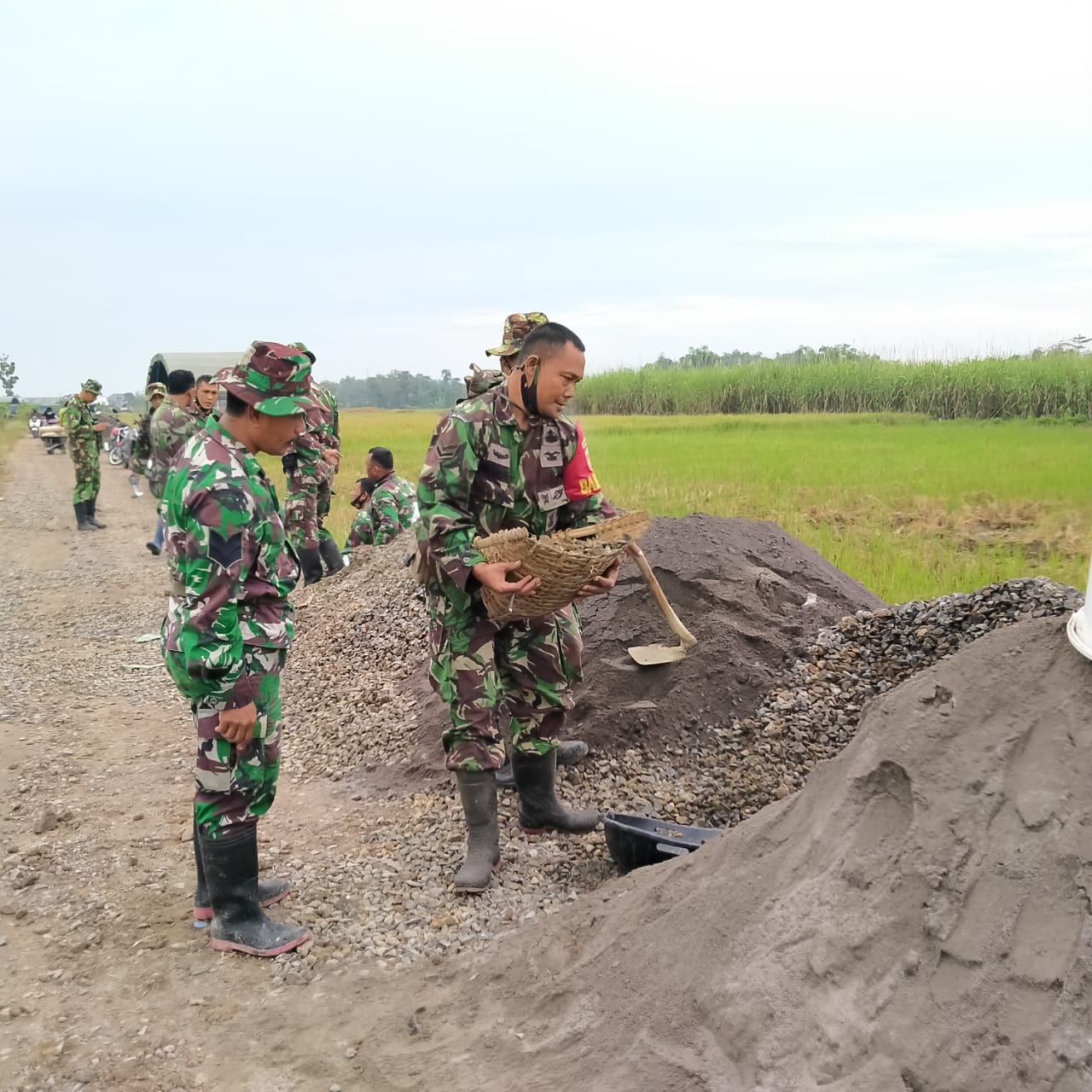 Anggota Satgas TMMD Siapkan Pasir, Koral, Dan Semen Untuk Dimasukkan Ke Dalam Mesin Molen