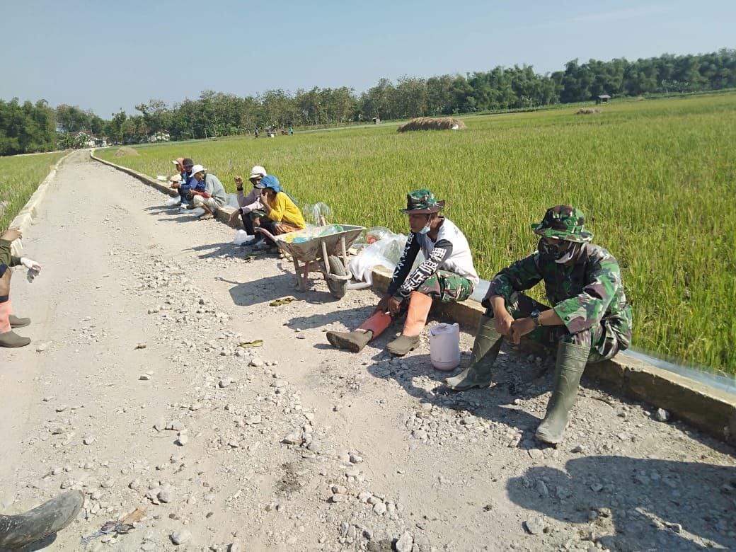 Anggota TMMD Dan Warga Istirahat Sambil Berjemur Dibawah Sinar Matahari Pagi Untuk Meningkatkan Imun Tubuh