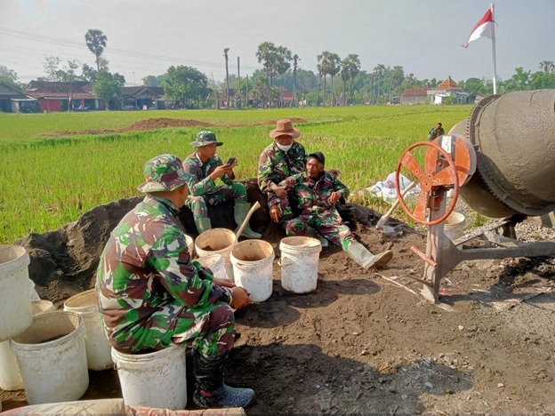 Canda Tawa Anggota Satgas TMMD Sambil Menunggu Adonan Semen Siap