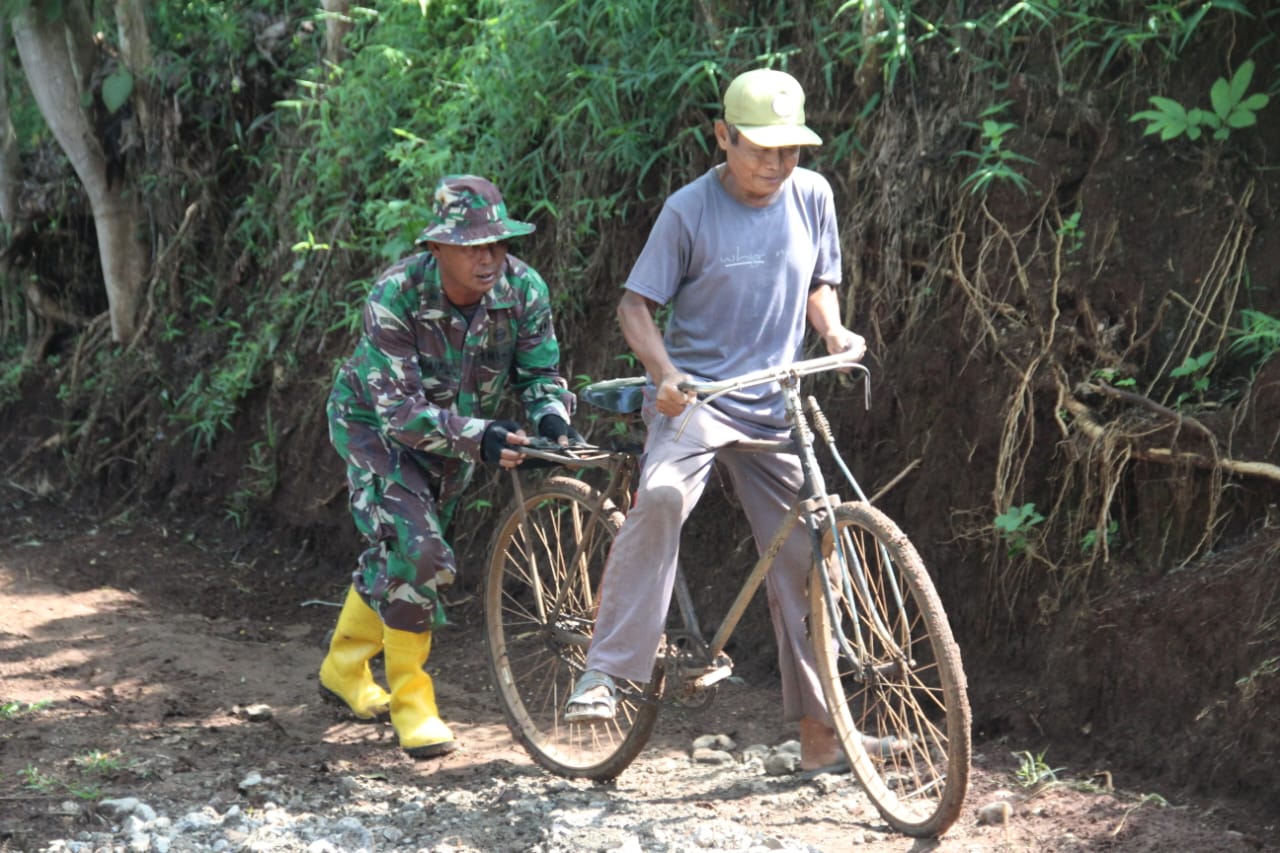 Jalan Licin, Satgas TMMD Bantu Warga Dorong Sepeda